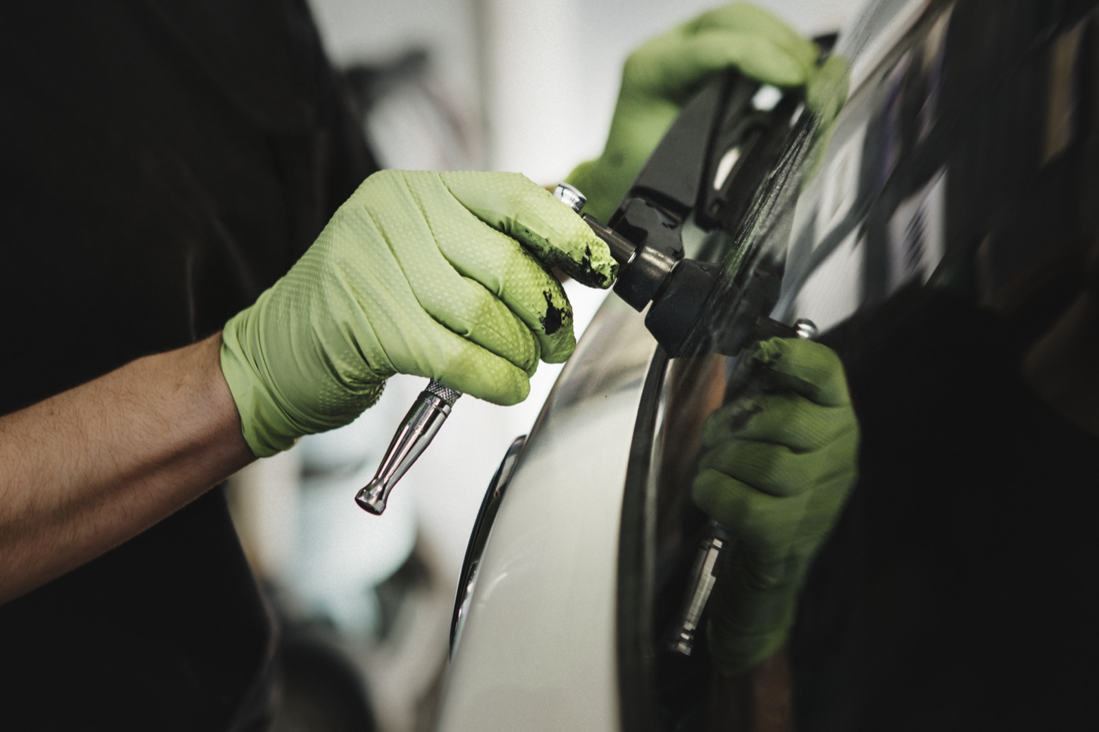 1Stop Dent Repair technician finishing a panel under shop lighting